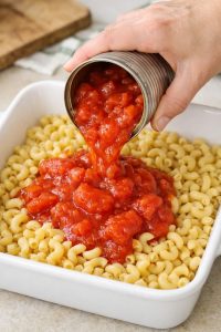 Pour canned stewed tomatoes and these 2 ingredients over uncooked elbow macaroni into a baking dish for a deeply comforting dinner your family will constantly crave