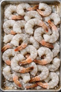 Put a bag of frozen raw shrimp onto a sheet pan and 2 simple additions to get a spring dinner so mouthwatering your friends will be begging for the re